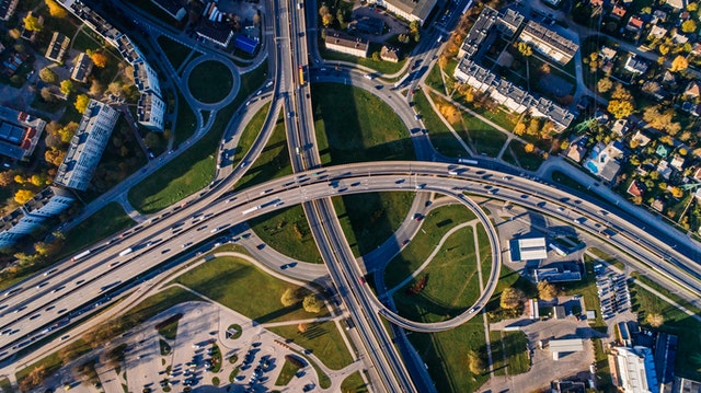 Aerial view of a complex highway interchange with multiple lanes, vehicles in motion, and surrounding greenery, illustrating road access and planning in Maryland.