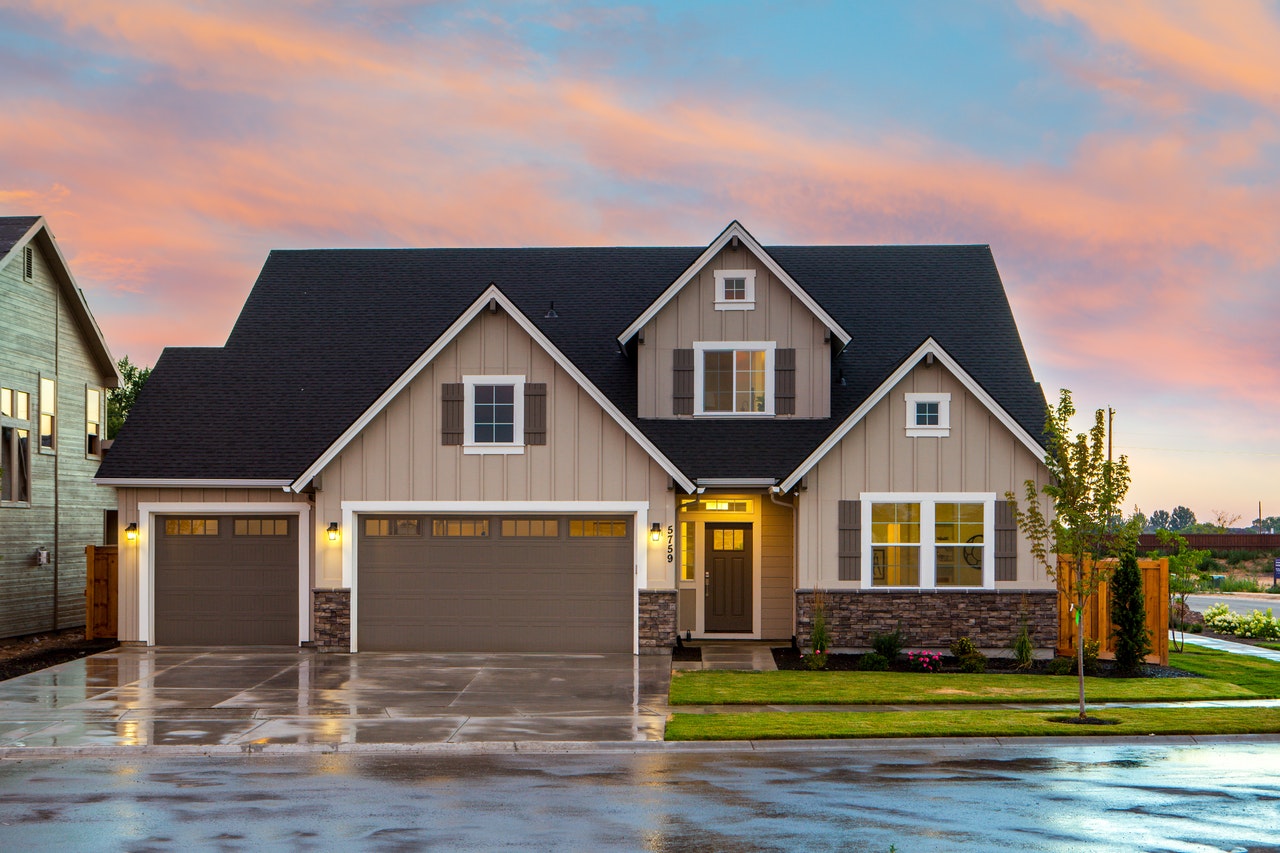 Custom home exterior with modern design, featuring a two-car garage, landscaped yard, and sunset sky, relevant to Maryland home building insights.